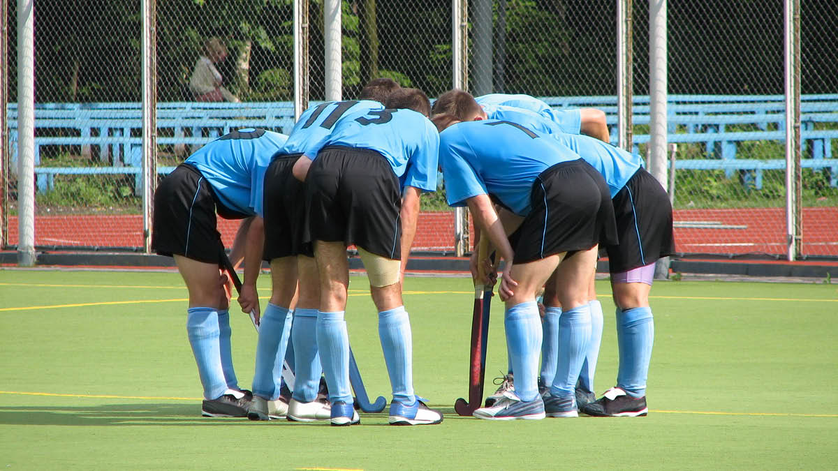 A hockey team in a huddle on the pitch